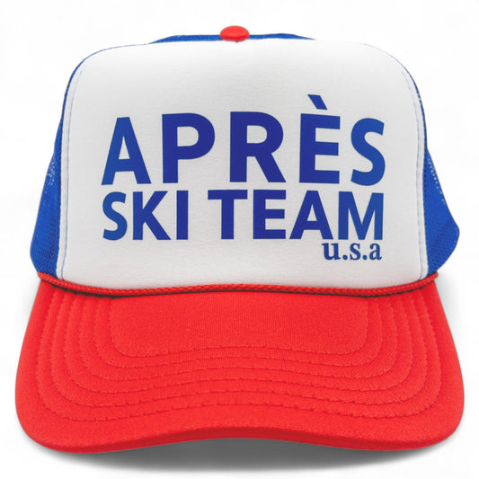 Red, white and blue foam trucker hat with blue mesh back and bold blue “Après Ski Team U.S.A” text on the front.