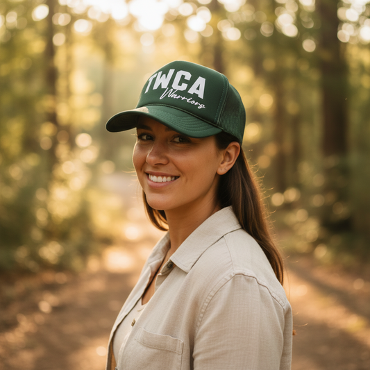Woman wearing a green cap with 'TWCA' logo in a forest setting