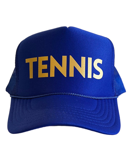 Blue cap with 'TENNIS' text on a stack of books in a room.